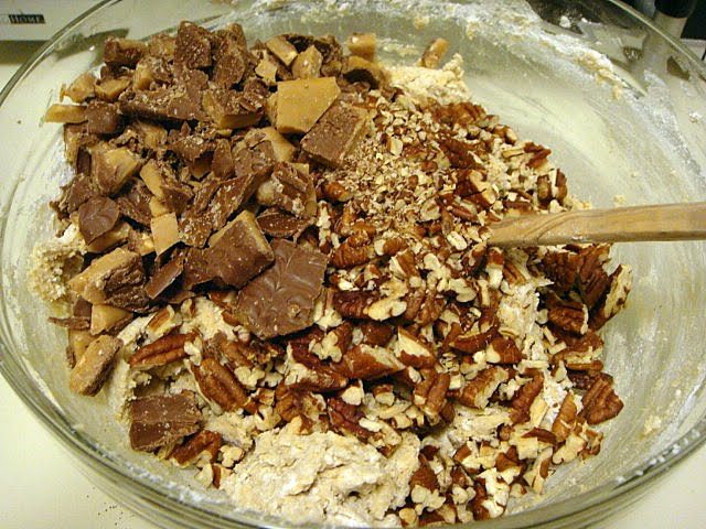 A bowlful of pecans, toffee, and other cookie ingredients ready to be mixed